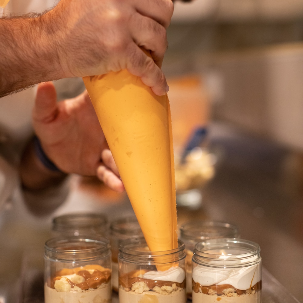 Produktion von Hand gefertigter Eislgläschen mit Eisparfait mit Haselnuss- und Chantilly-Creme-Geschmack, salziger Karamellsauce und glutenfreies Haselnusscrumble 
